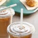 A plastic cup with a lid and two EcoChoice PLA straws in drinks on a table in a coffee shop.