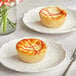 Two September Farm Strawberry Cheese Tarts on plates with forks.