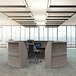 A Correll curved ash laminate reception counter with a computer on it in a modern office.