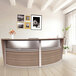 A Correll walnut laminate curved reception desk with a counter.