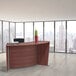 A Correll cherry laminate ADA curved reception desk in a modern office with a view of a city.