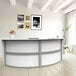 A white and gray Correll curved reception counter with a white plant on it.