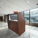 A Correll cherry wood reception desk with a see-through top panel.