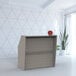 A Correll ash laminate reception desk with a red clock on it.