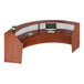A Correll cherry laminate curved reception desk with a computer and keyboard.