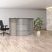 A Correll curved corner reception desk with an ash laminate finish.