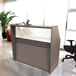 A brown wooden Correll reception desk with a see-through glass counter panel.
