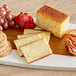 A block of September Farm Chipotle Cheddar cheese on a cutting board with cheese, grapes, and strawberries.