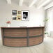 A Correll walnut laminate curved reception desk with a wooden top.