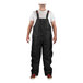 A person wearing Tingley black overalls over a white shirt.