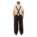 A man wearing Tingley black overalls with red suspenders.