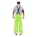 A man wearing Tingley Vision Class E Hi-Vis lime overalls with reflective stripes over a white shirt and black suspenders.