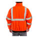 A person wearing a Tingley orange safety jacket with black panels and reflective stripes.