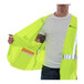 A man holding a Tingley Hi-Vis yellow safety vest with reflective stripes and a pocket.