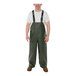 A man wearing green Tingley rain overalls with suspenders.