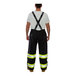 A man wearing black Tingley Icon overalls and black suspenders over a white shirt.