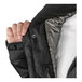 A person's hand holding a black Tingley insulated jacket with a detachable hood.