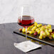 A Stolzle Quatrophil Bordeaux wine glass filled with red wine next to grapes on a table.