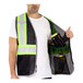 A man wearing a black Tingley safety vest with reflective tape and a black mesh pocket.