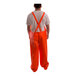 A person wearing an orange Tingley rainsuit with suspenders.