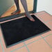 A woman standing on a black Cactus Mat with shoes on.