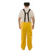 A man wearing yellow Tingley rain overalls with suspenders.