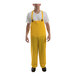 A man wearing a yellow Tingley rainsuit with overalls.