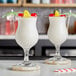 Two glasses of white Pina Coladas with pineapple and cherry.