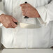 A person in a white coat using a Mercer Culinary knife sharpening steel to sharpen a knife.