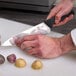 A person cutting potatoes with a Mercer Culinary chef knife.