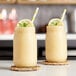 Two glass jars of yellow liquid with straws and lemon slices.