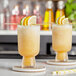 Two glasses of organic frozen citrus cocktails with lemon and lime slices and straws.