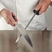 A hand holding a Mercer Culinary knife and a black knife sharpening steel.