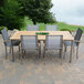 A Three Birds Casual Avanti teak table and chairs on a stone patio.