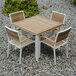 A Three Birds Casual SoHo stacking arm chair with white frame on a wood table on gravel.