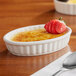 An Acopa ivory porcelain creme brulee dish with a strawberry on top.