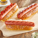 Three Vienna Beef skinless hot dogs on a cutting board with ketchup and mustard.