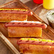 Three Vienna Beef skinless beef hot dogs on a wooden tray with mustard and ketchup.