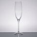 A clear Stolzle flute glass with a single stem on a table.