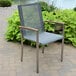 A Three Birds Casual Avanti stacking arm chair on a brick patio.