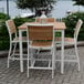 A Three Birds Casual SoHo counter height side chair with a white frame and wooden seat on a brick patio.