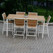 A Three Birds Casual teak dining table and chairs on a brick patio.