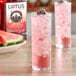 A glass of pink Lotus Plant Power Skinny Sugar-Free Red Lotus Energy Drink with ice and berries.