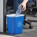 A person putting a plastic bottle in a blue Lavex recycling bin.