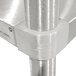 A close-up of a stainless steel Advance Tabco mixer table corner with a galvanized metal pole.