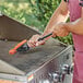 A man using a Mr. Bar-B-Q grill brush to clean a grill.