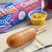 A State Fair classic corn dog on a napkin next to a bag of mustard.