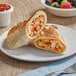 A plate with two Clara's Kitchen Plant-Based Vegan Bean and Cheese Breakfast Burritos and a bowl of fruit.