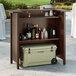 A Lancaster Table and Seating portable bar with a cooler and bottles on top.