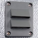A grey rectangular metal wall plate with two holes.